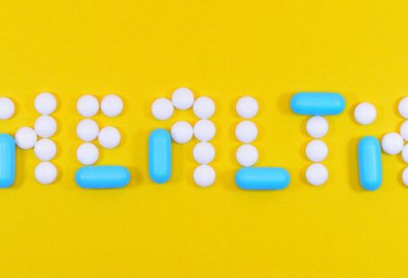 Health Insurance - White and Blue Health Pill and Tablet Letter Cutout on Yellow Surface