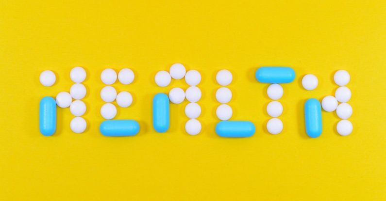 Health Insurance - White and Blue Health Pill and Tablet Letter Cutout on Yellow Surface