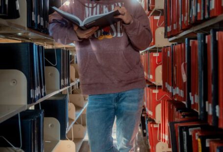 Student Loans - Man Reading Book In Library
