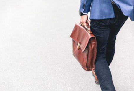 Job Search - person walking holding brown leather bag
