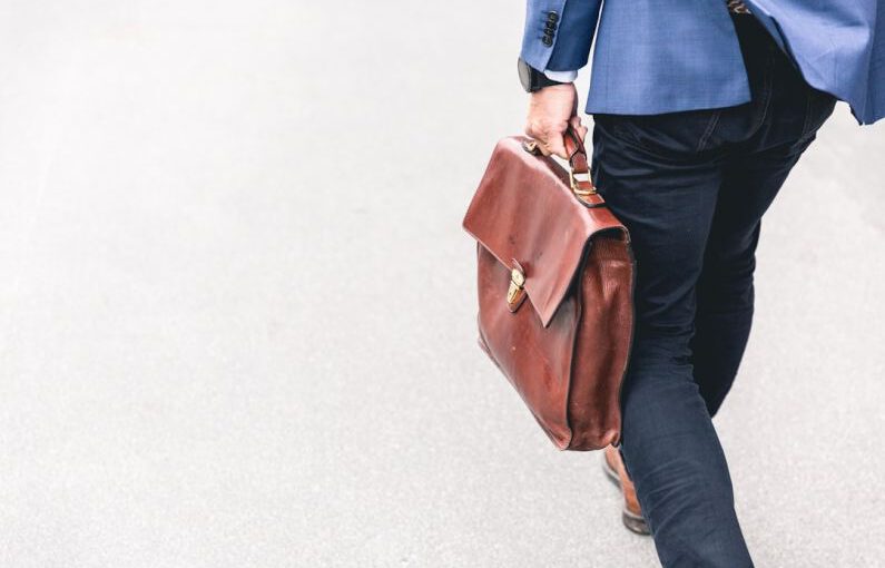 Job Search - person walking holding brown leather bag